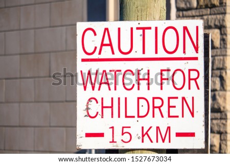 A sign in a housing development under construction warns drivers to watch for children, and sets a speed limit of fifteen kilometers per hour.