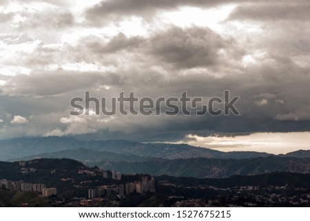 Rainy sky over mountains and buildings.