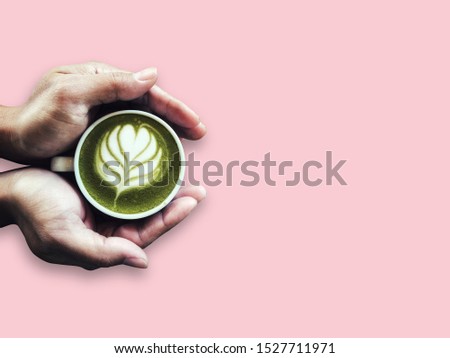 Hands man holding Latte art green tea cup  isolated on pink pastel background. Green tea latte on hands. vintage and pastel concept. 