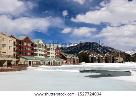 Colorado nature background, ski resort vacation concept. Scenic view with Keystone sky resort downtown and mountains around the covered by snow and thawed ice lake in spring sunlight. 