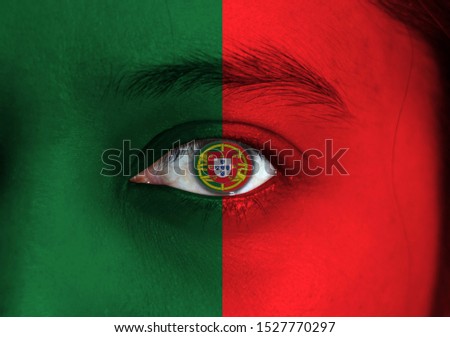 Human face painted Portuguese flag with coat of arms of Portugal on the center of eye or eyeball. Human eye painted with flag of Portugal.