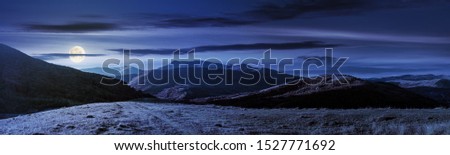 wonderful panorama of mountain ridge in autumn. gorgeous landscape with rolling  hills and meadows in weathered grass in full moon light. sunny weather with fluffy clouds on the sky at night Royalty-Free Stock Photo #1527771692