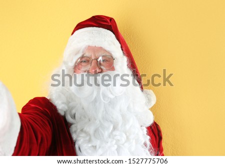 Authentic Santa Claus taking selfie on yellow background
