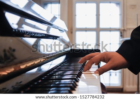 The girl's hand is placed on the piano keys and is playing the piano so the audience at the party can listen to the melodious sound of the piano which is the ultimate of classical music.