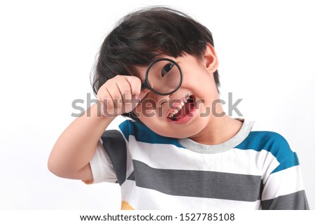 Portrait of Asian boy using magnifying glass. Cute little boy look through the magnifying glass and his eye is enlarged Royalty-Free Stock Photo #1527785108