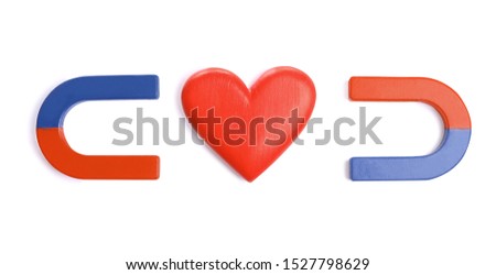 Red and blue horseshoe magnets with decorative heart on white background, top view