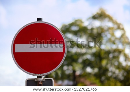 A red round sign warns: entrance forbidden. It is a one way street. In the background a tree, out of focus with beautiful bokeh.