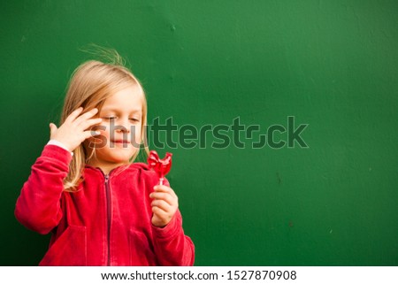 Baby with red candy on a green background.