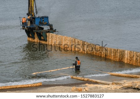 SEA COAST - Workers strengthen the sea shore by building groyne from wooden piles