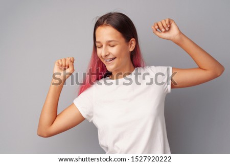 Happy young teen girl winner celebrating success over gray background Royalty-Free Stock Photo #1527920222