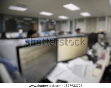 Blurry background of super busy working space with two screen monitors and a lot of papers on the desk