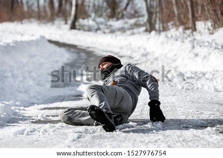 Injured man lying on the road, downfall and accident on winter season, black ice  Royalty-Free Stock Photo #1527976754