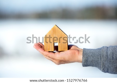 Male´s Hand holding a small wooden house, planning for the future, real estate
