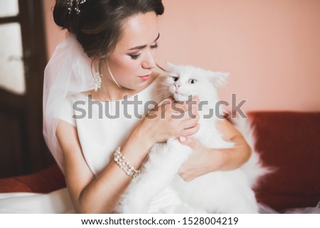 Beautiful bride wearing fashion wedding dress with feathers with luxury delight make-up and hairstyle, studio indoor photo shoot