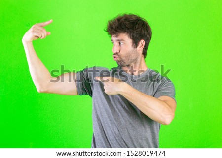 Crazy strong young man pose on green background