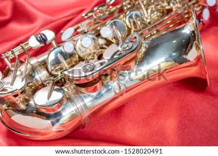 Beautiful macro photo of the details of a musical wind instrument of a golden alto saxophone on a red background