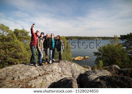 Group of friends  standing on the rock and taking selfie picture at Baltic sea background 