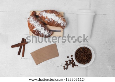 Coffee cup mock-up with croissant on white table, top view