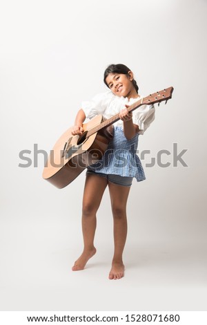Indian Cute little Girl holding guitar against white background. 