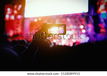 Hands with a smartphone records live music festival, Taking photo of concert stage.