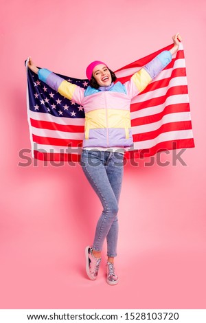 Pretty lady making photos with usa flag glad to visit new country wear warm colored coat isolated pink background
