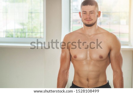 Fitness instructor in the sport room background. Male model with muscular fit and slim body. Sport concept