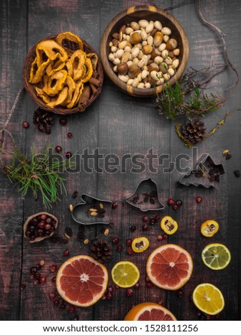 Food background with christmas spices, dried apples, nuts, citrus fruits, cydonia, cranberries, raisin, and baking dish on wooden background. Copy space for christmas recipe.