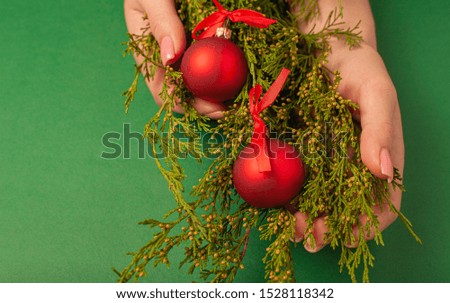 Christmas background with pine toys and female hands. Top view on a green background.