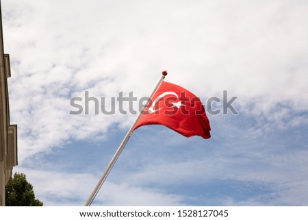 Waving Turkish flag against a partially blue sky.