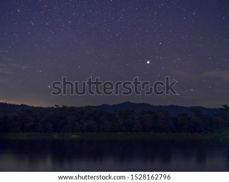 Deep night sky with many stars over forest & river background