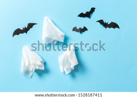 White ghost sheet costume against pastel blue background. Minimal Halloween scary concept.