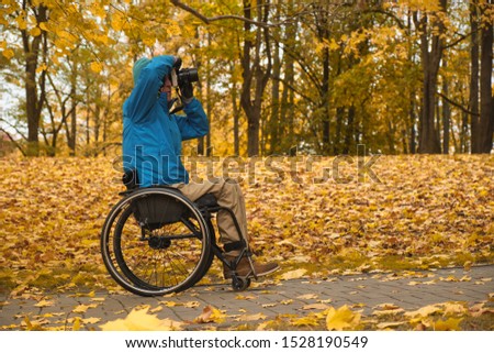 photographer on the wheelchair in yellow autumn park, photographer with disability