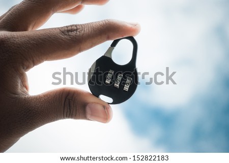 number lock held in hand on blue bright sky background