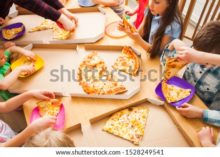 Happy children eating pizza enjoying birthday party in cafe
