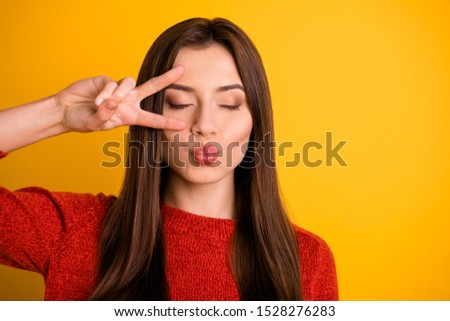 Close up photo of charming peaceful girl have date with her boyfriend send air kisses make v-signs with her eyes closed wear red jumper isolated over yellow color background