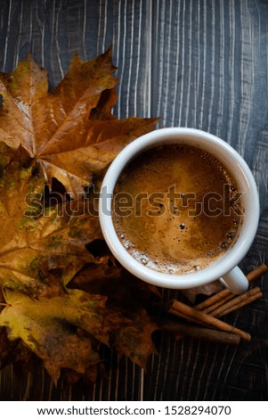 Mug of coffee with cinnamon and some whitered leaves. Flat lay. Vertical