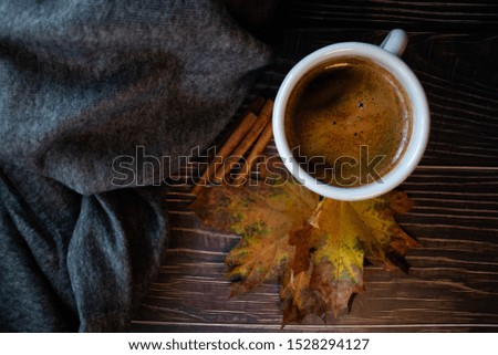 Cosy morning coffee with warm blanket, fall leaves and cinnamon, on a wooden table