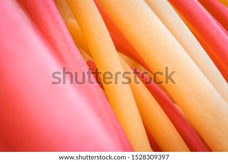 Red, yellow and orange stripes, colourful foam sticks. Background and colors concept.