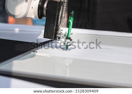 Robotic hand draws a picture with a green pen. Science and high technologies concept.