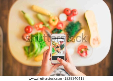 Girl makes photo on smartphone ingredients for cooking. Photo of fresh vegetables. Culinary blog. Lifestyle.Grain photo in retro style.