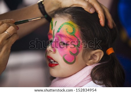 Little girl having face painted on party