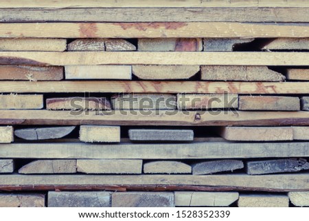Folded wooden brown and gray planks. A pile of boards stacked on top of each other.Lumber for use in construction