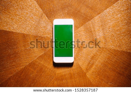 A flat lay of smartphone with green screen on a table