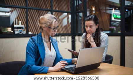 young HR woman interviews a candidate for a job. Business meeting two young women at work discussing the project. Two women in the office at the table, looking at gadgets and discussing something