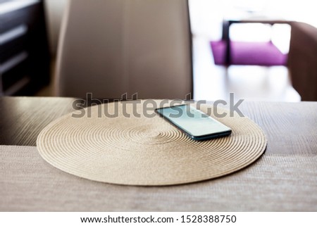 Single smartphone left on the table in the living room, one unattended mobile phone device laying on a coaster screen on scene data security, leaving your tech on the table concept.  Copy space nobody Royalty-Free Stock Photo #1528388750