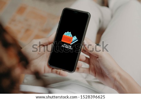 Hands holding a Phone with a sign of Online Payments.