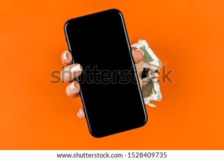A woman holds a phone through ragged orange drywall Royalty-Free Stock Photo #1528409735