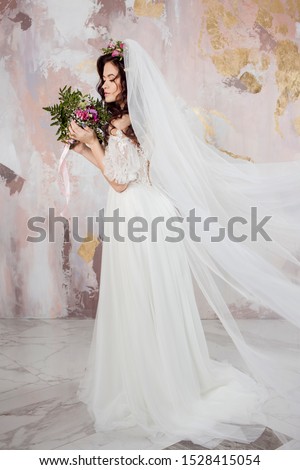Beautiful young bride in wedding dress with veil on her face. textured background in pastel colors