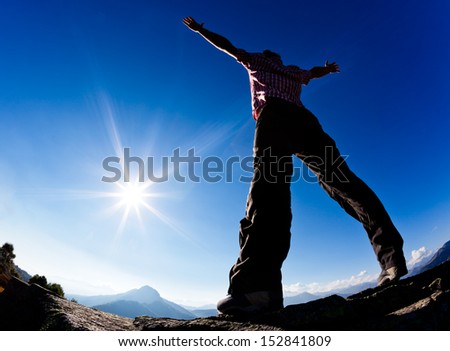 Man opens his arms in the sunshine against blue sky. Concept: freedom, success, energy, vitality.