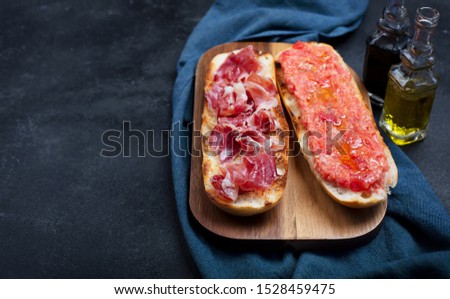 Spanish tomato and jamon toast, traditional breakfast or lunch on black background with copy space